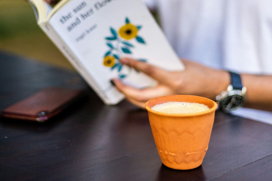 Person sitting infront of a table with a clay cup of chai