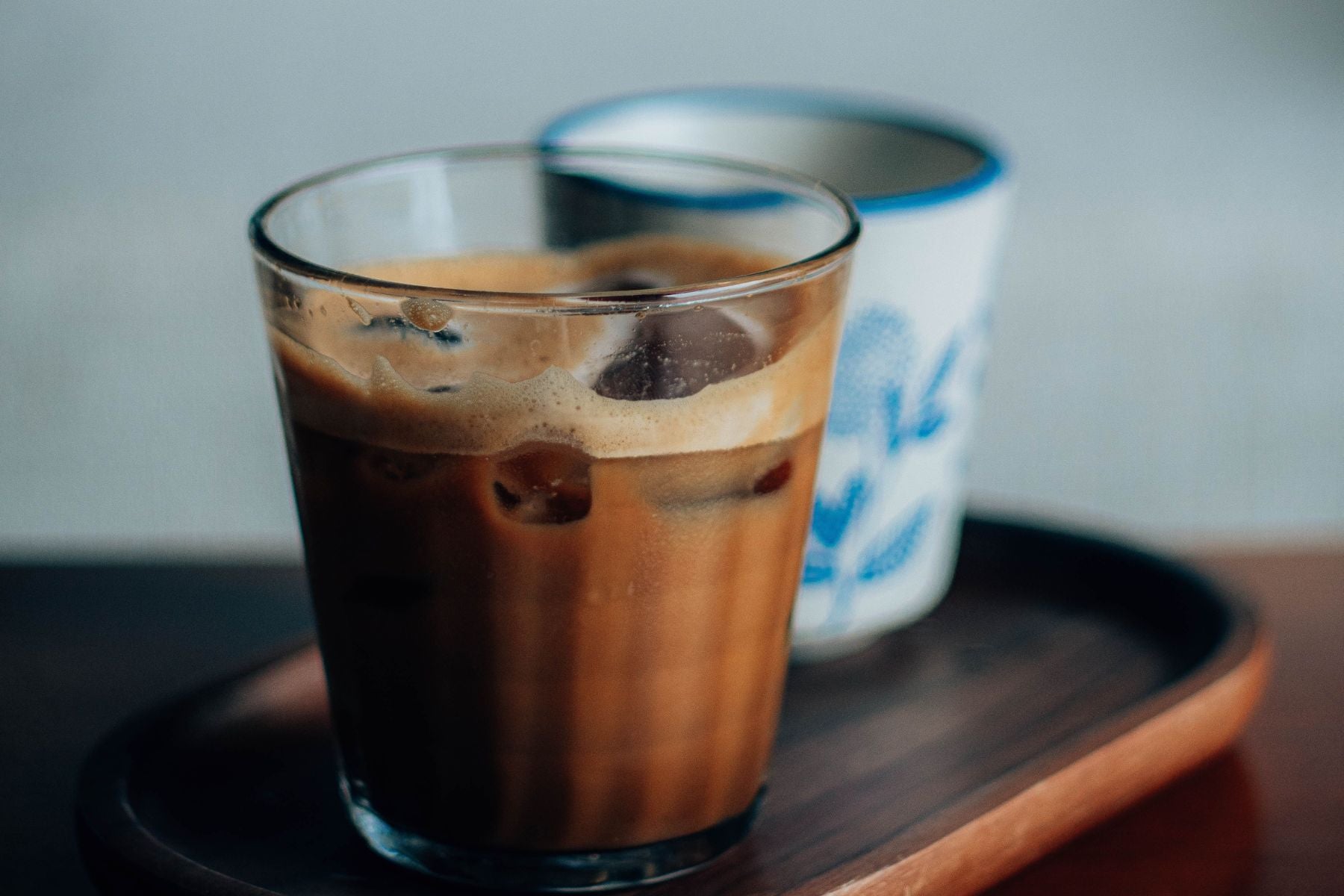 A glass of Iced Chai Tea Latte on plate placed on a wooden table