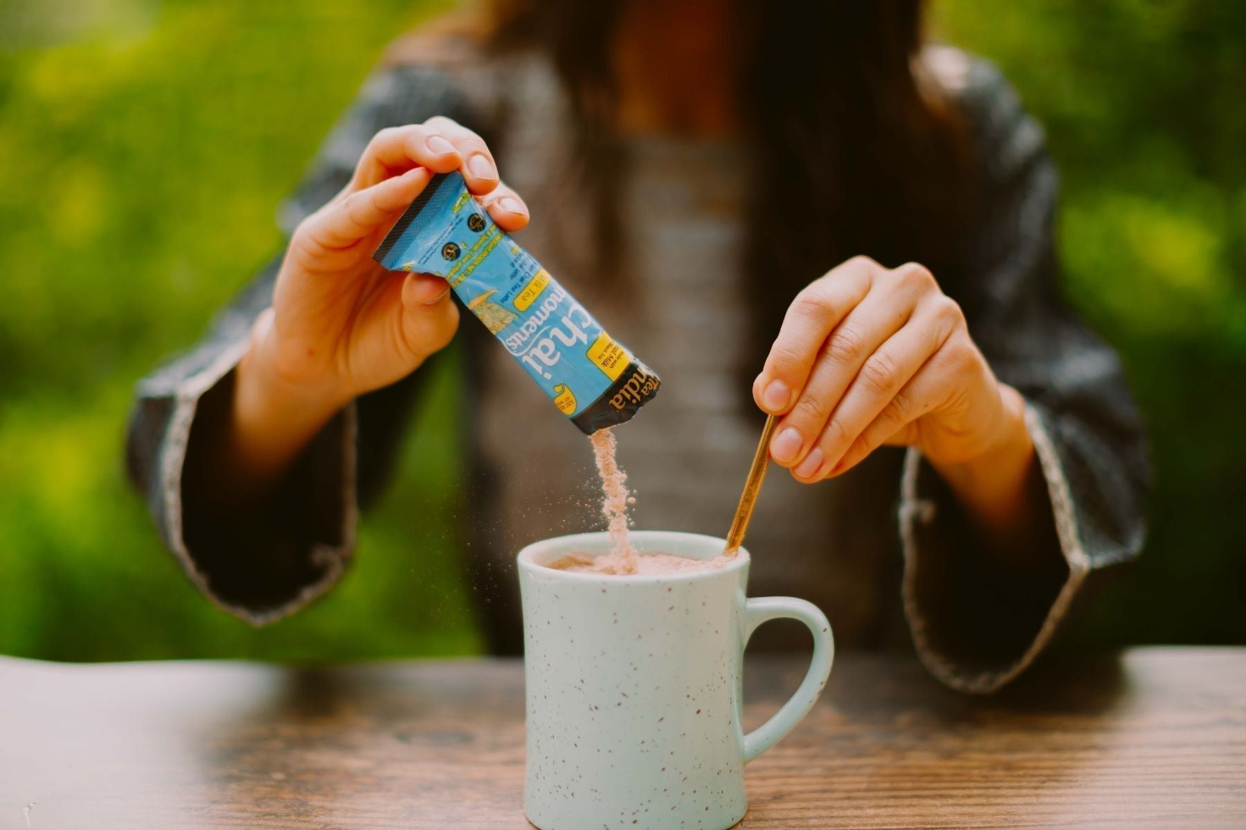 Pouring a Milk Tea Chai Moments sachet into a mug.