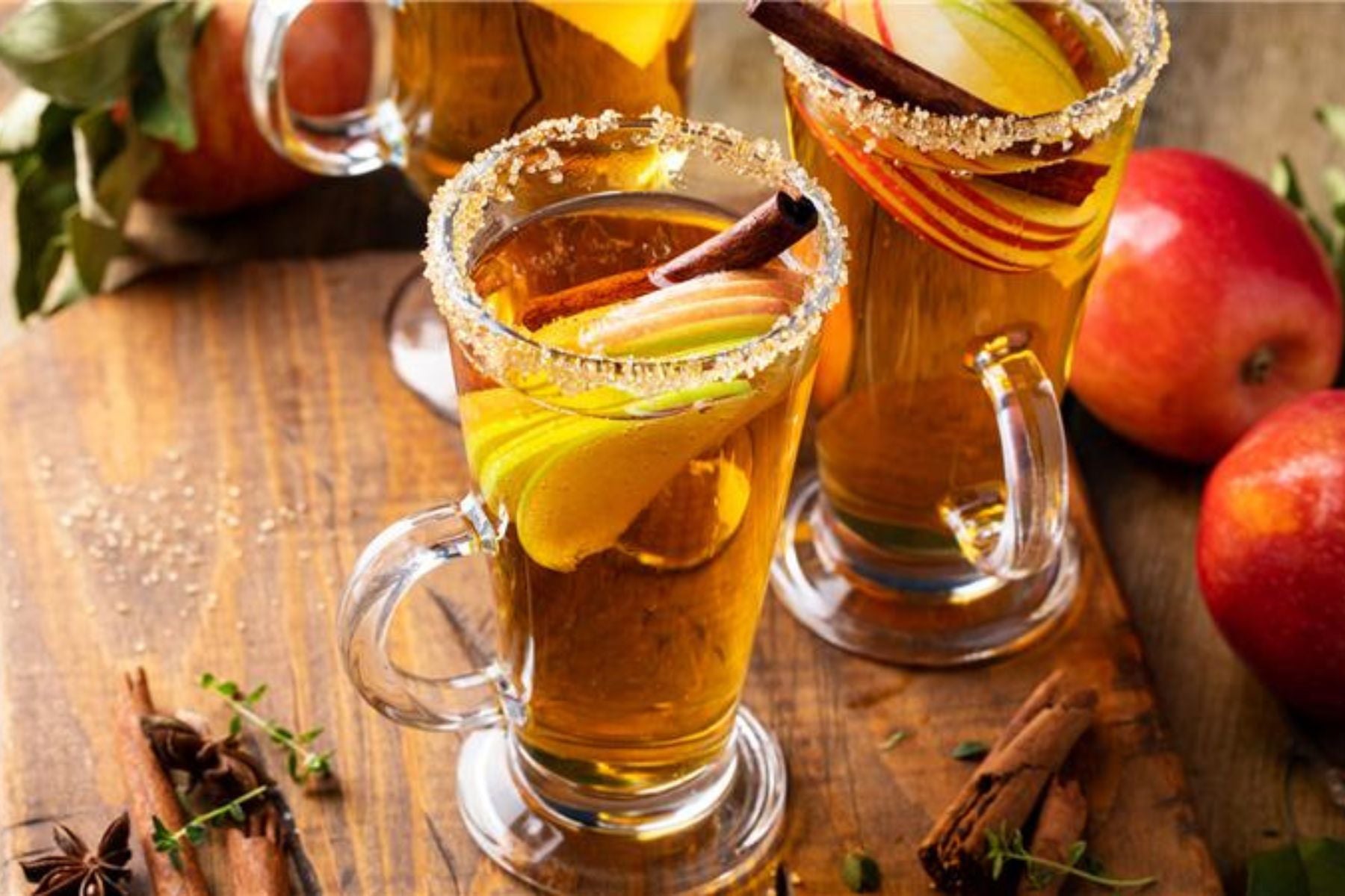 Spiced apple mocktail with sugar rims and cinnamon sticks.