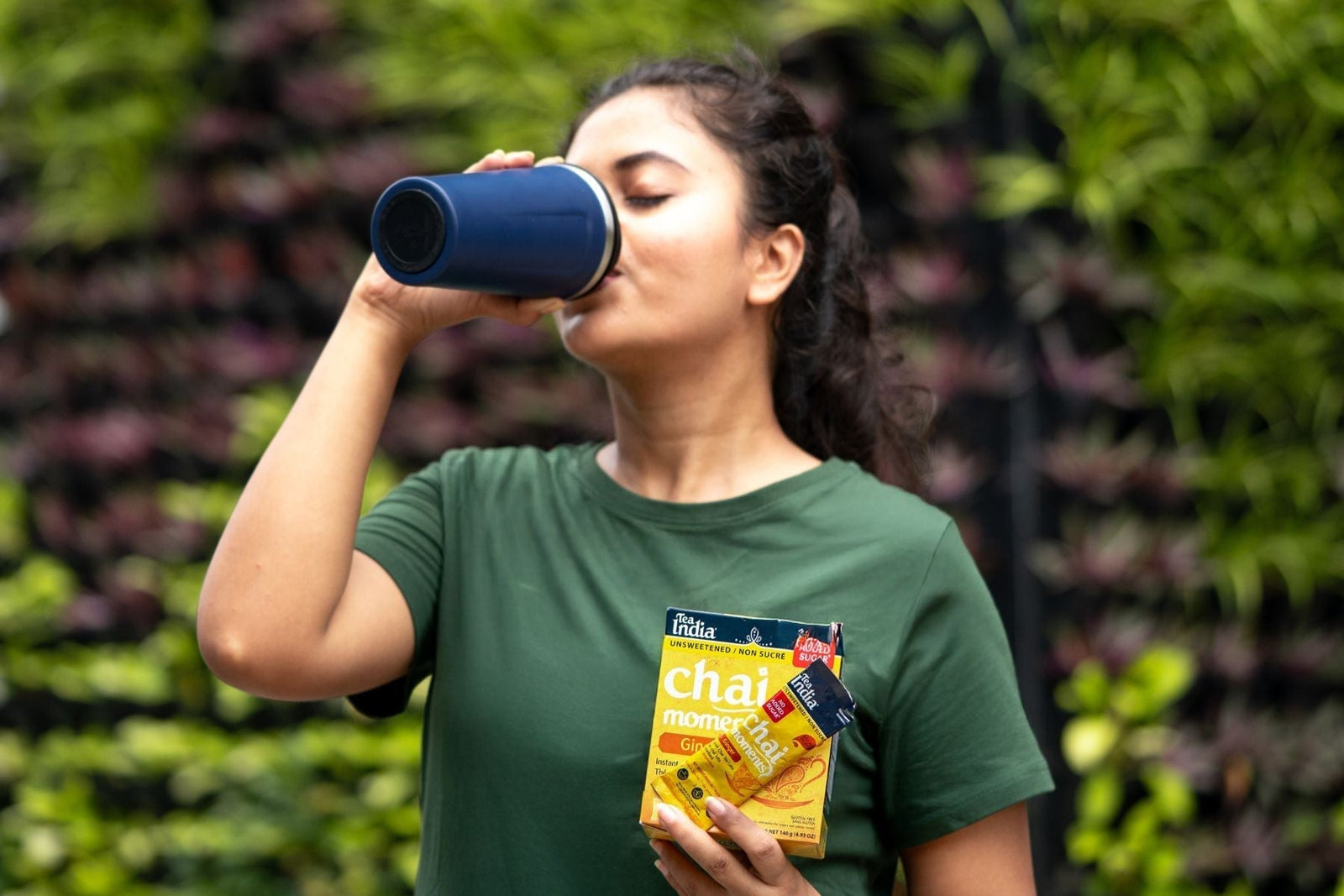 A person drinking Tea India tea holding ginger chai Moments box