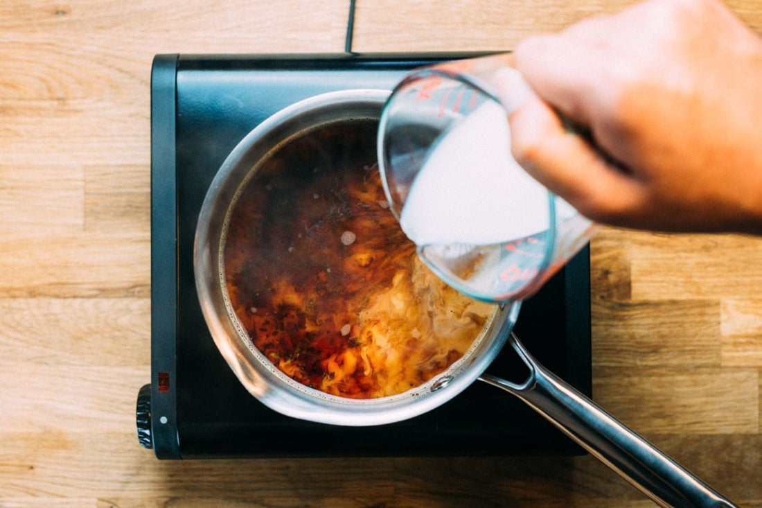 Milk being poured into a saucepan full of tea