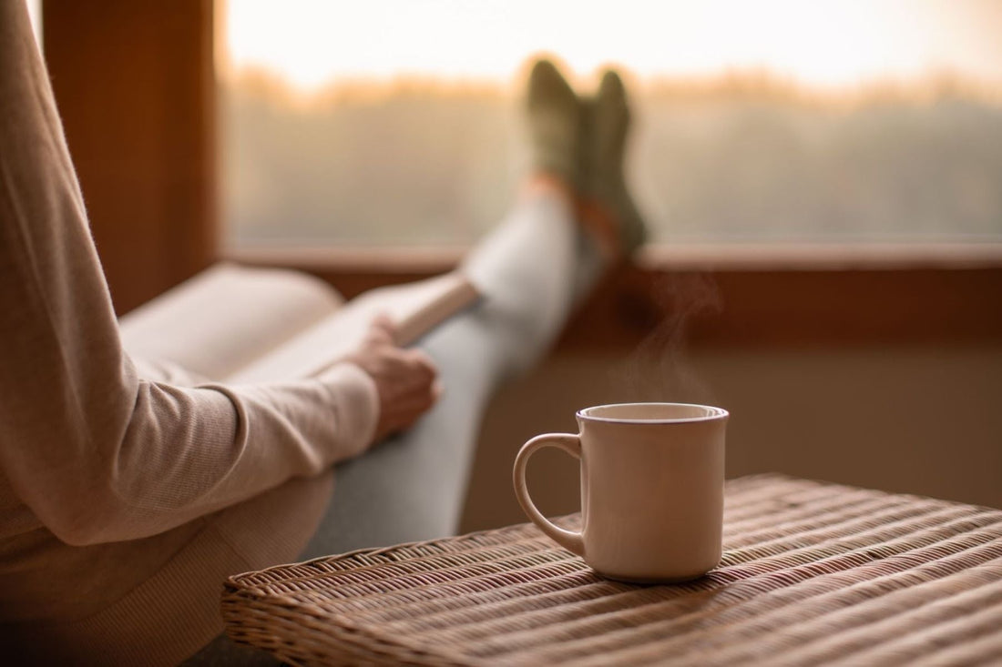 A person reading a book while having tea