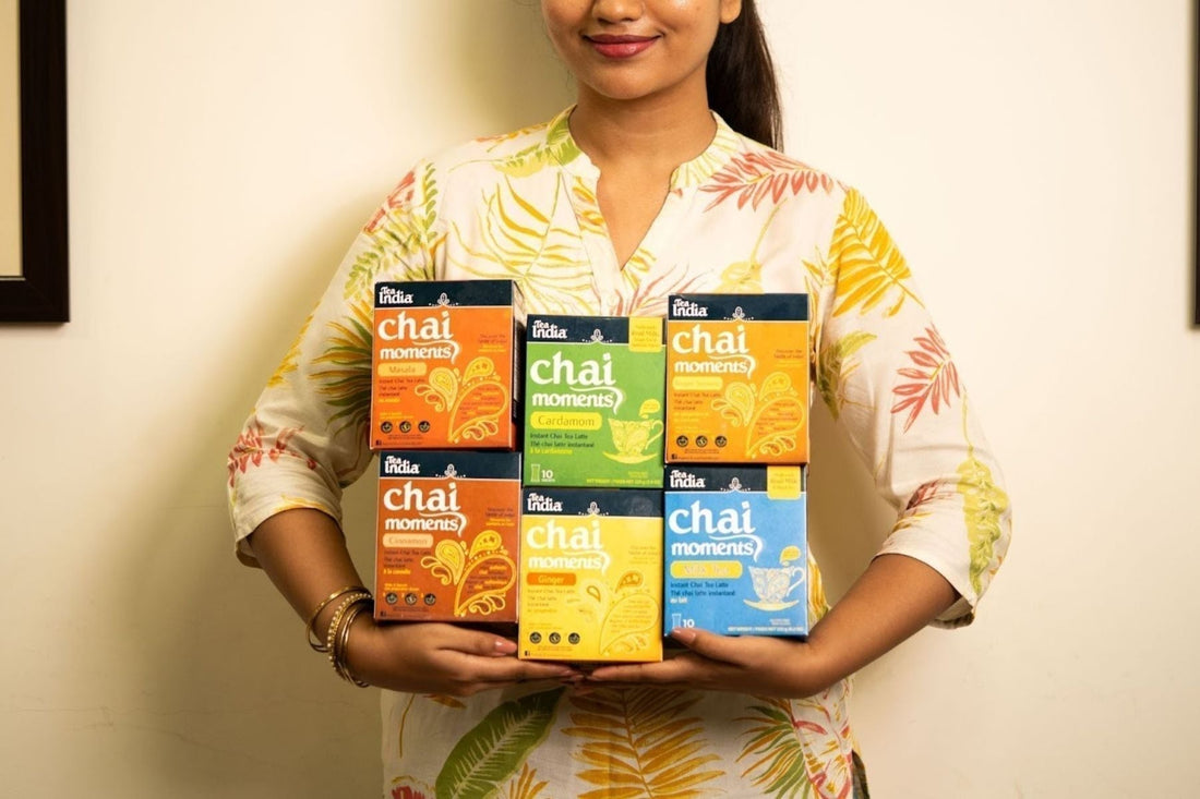 A person holding boxes of Tea India Instant Chai Mix