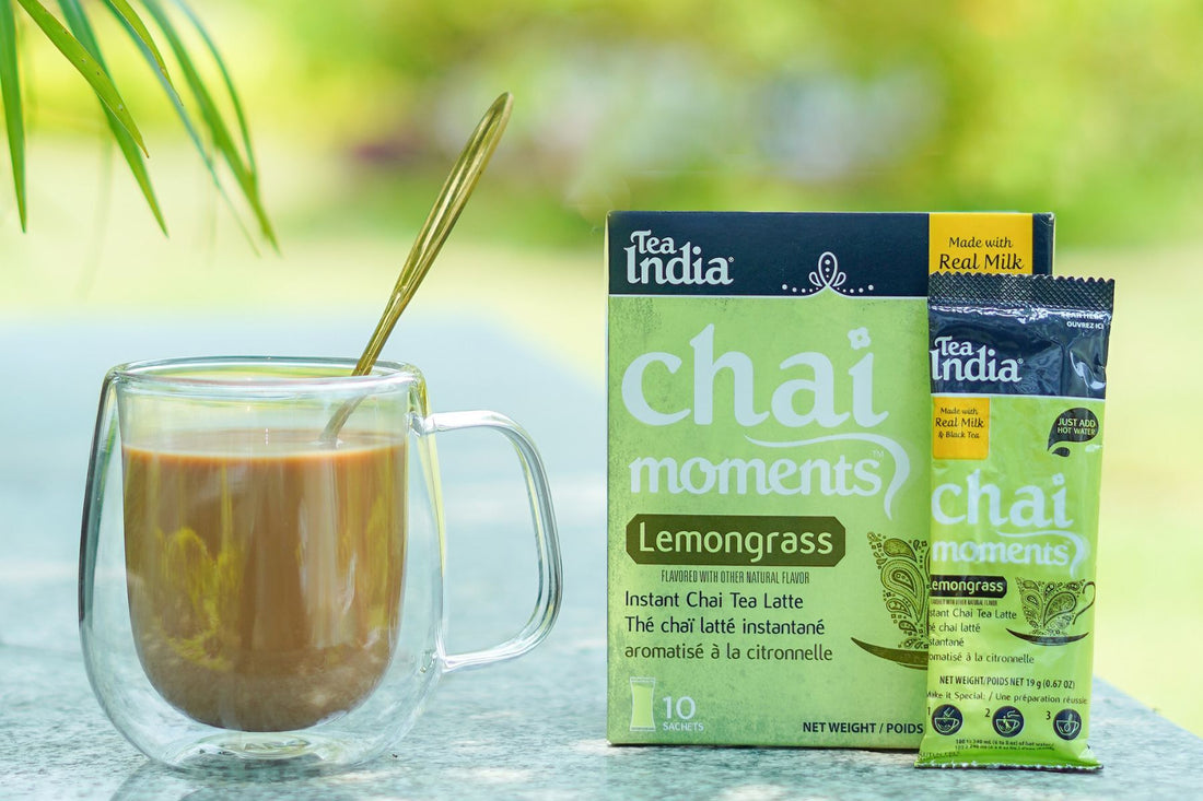 a box of Tea India Instant Lemongrass premix with a cup of chai placed on steps in broad daylight