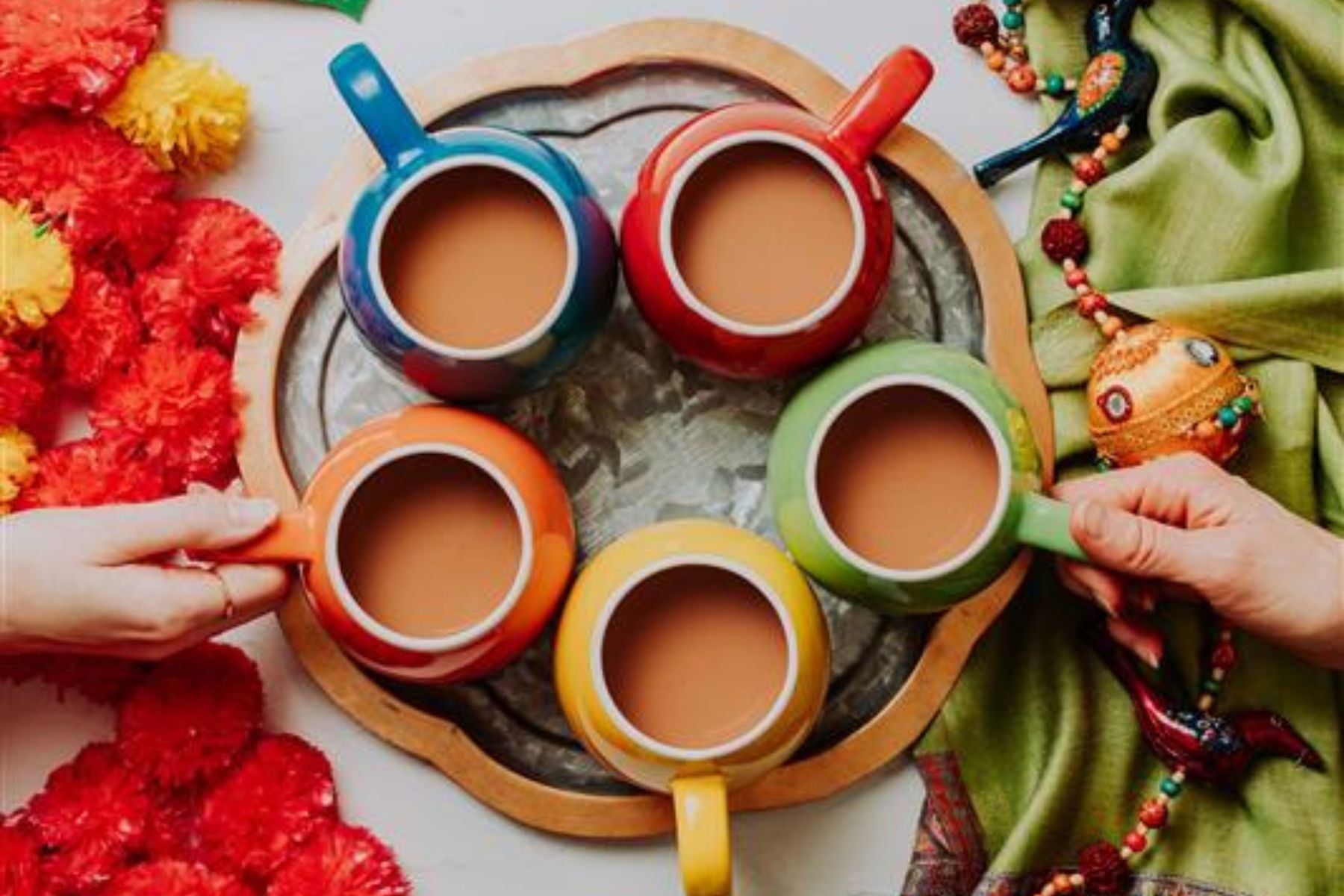 Colorful cups of chai arranged on a tray with festive decor
