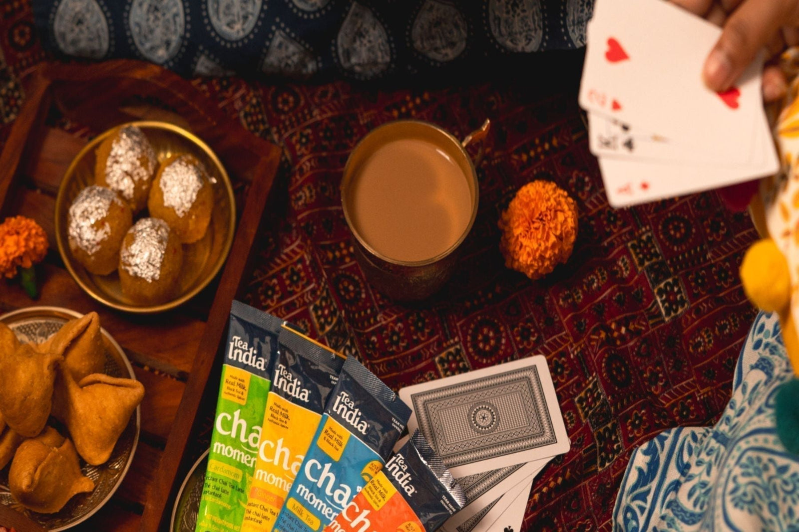Cup of chai with Tea India Tea sachets, snacks, sweets, and a deck of cards