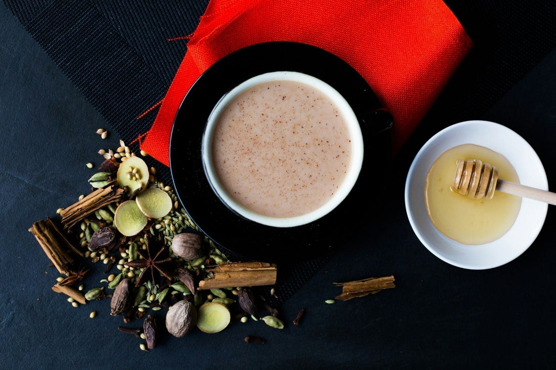 Cup of chai with honey and scattered masala spices