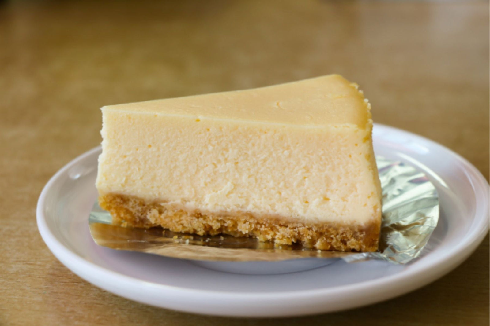 Slice of plain baked cheesecake on a white plate.