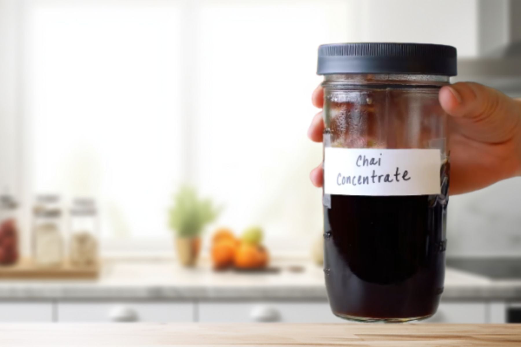 Hand holding jar of homemade Chai Concentrate.