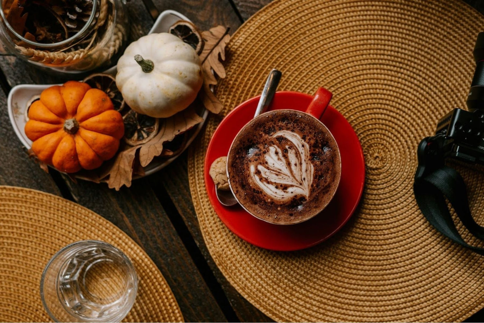Overhead view of a Pumpkin Chai latte and mini pumpkins on a wooden table.