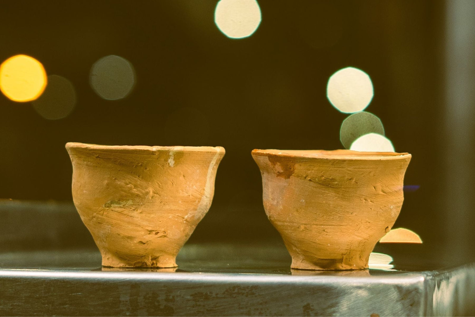 2 mud made tea cups kept on glass table