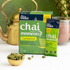 Tea India Chai Moments Cardamom packaging with a brass teapot and cardamom pods on a white surface.