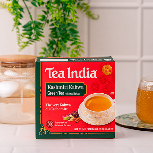 Box of Tea India Kashmiri Kahwa Green Tea on a kitchen counter with a candle and glass mug in the background.