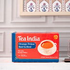 Box of Tea India Orange Pekoe Black Tea Blend on a kitchen counter with decorative plates in the background.