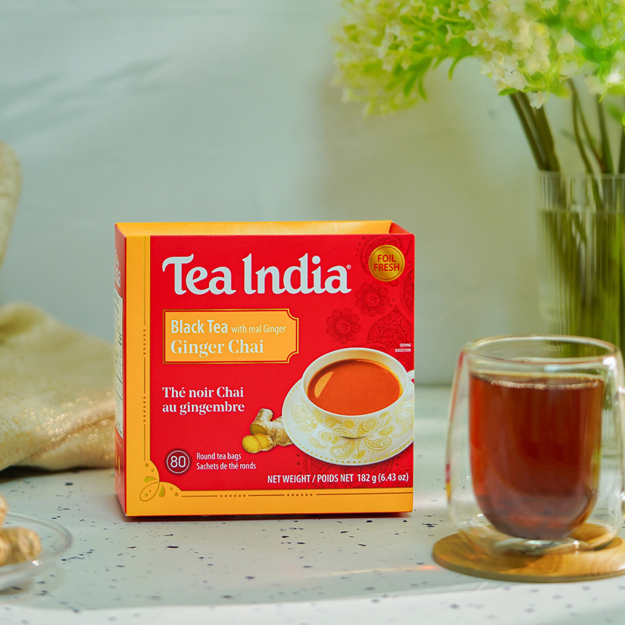 Box of Tea India Black Tea with Ginger Chai on a table with a glass of tea.