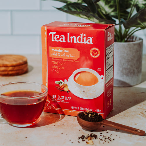 Tea India Masala Chai box with a cup of tea and wooden spoon on a table.