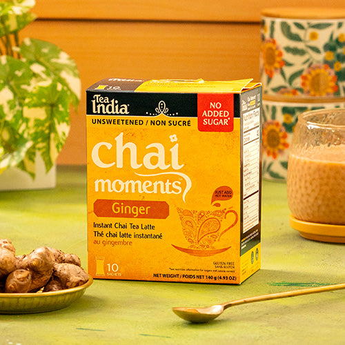 Box of Tea India Chai Moments Ginger No Added Sugar instant chai tea latte on a table with ginger and a cup in the background.