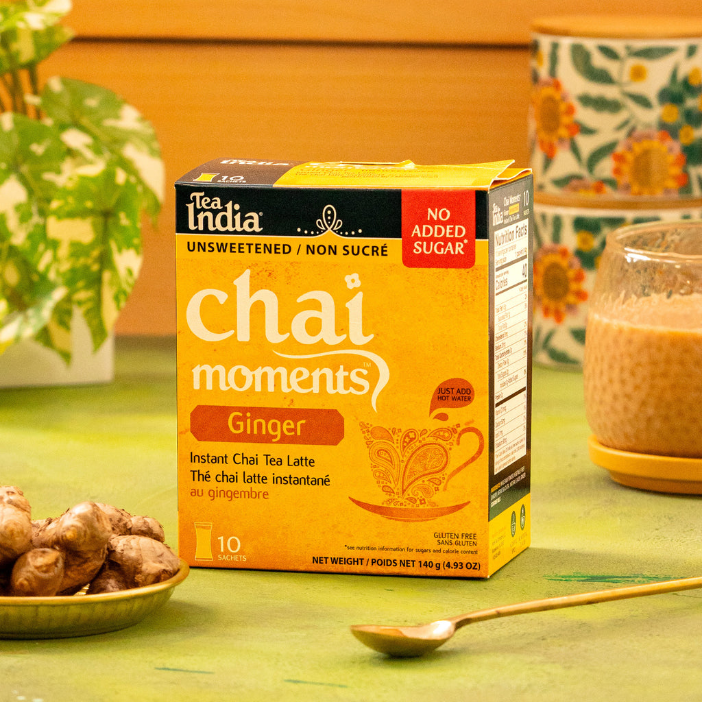 Box of Tea India Chai Moments Ginger No Added Sugar instant chai tea latte on a table with ginger and a cup in the background.