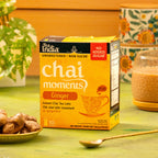 Box of Tea India Chai Moments Ginger No Added Sugar instant chai tea latte on a table with ginger and a cup in the background.