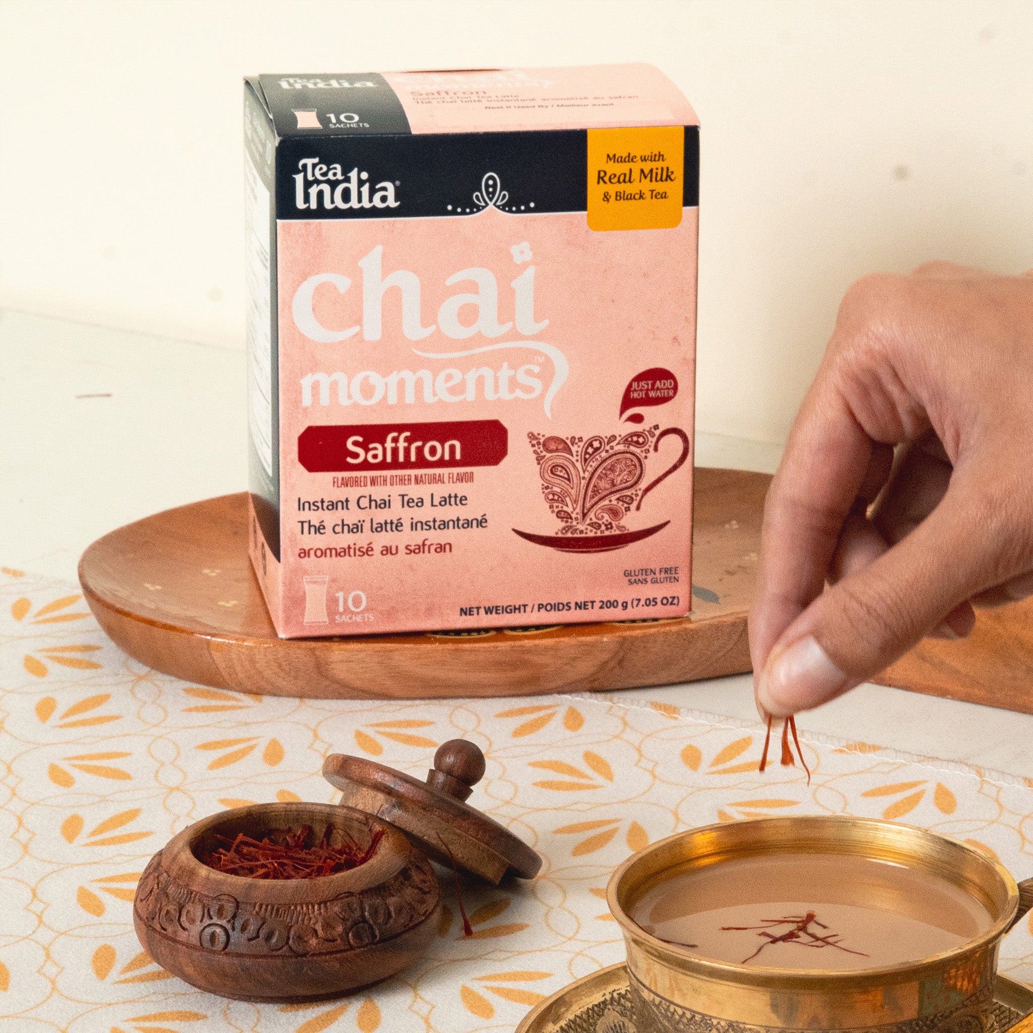 Tea India chai moments saffron instant chai tea latte packaging with a hand adding saffron to a cup.