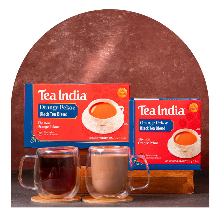 Two boxes of Tea India Orange Pekoe Black Tea Blend with two glass mugs filled with tea on a wooden stand.