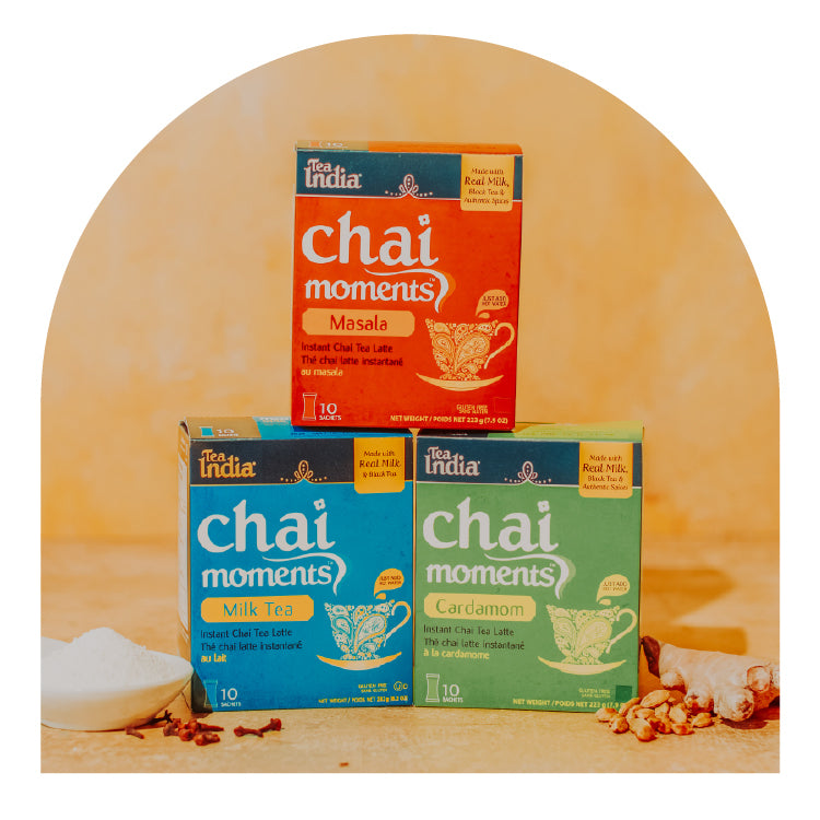 Three boxes of Tea India Chai Moments on a wooden surface with a yellow arch background.