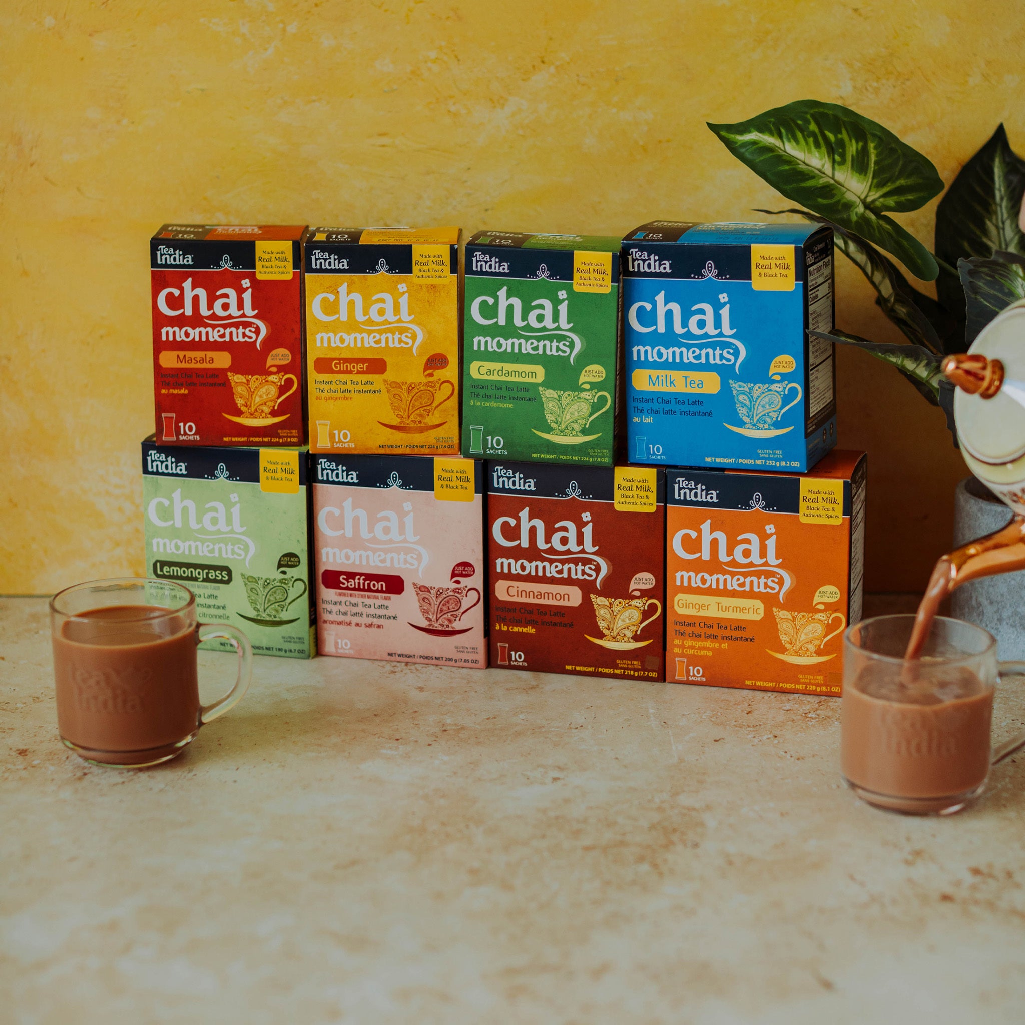 Stack of 8 instant latte 'chai moments' tea boxes with a yellow background and 2 cups of chai