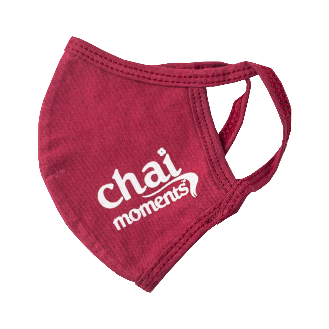 A maroon cloth face mask featuring the white &quot;chai moments&quot; logo printed on the side.