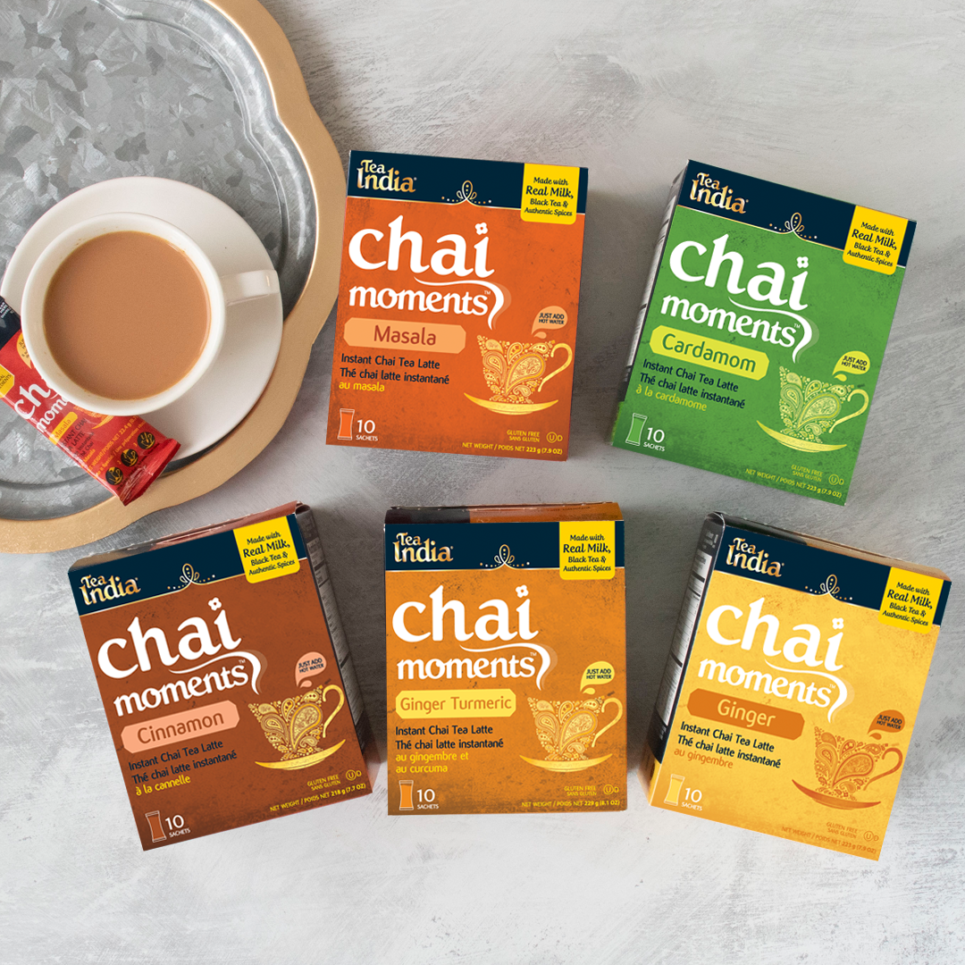 Five Tea India Chai Moments instant latte mix boxes in Masala, Cardamom, Cinnamon, Ginger Turmeric and Ginger flavors, with a cup of prepared chai and a sachet